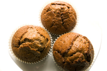 Three gingerbread muffins in cups on a plate.