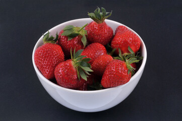 Bol de fraises gariguettes en gros plan sur fond noir