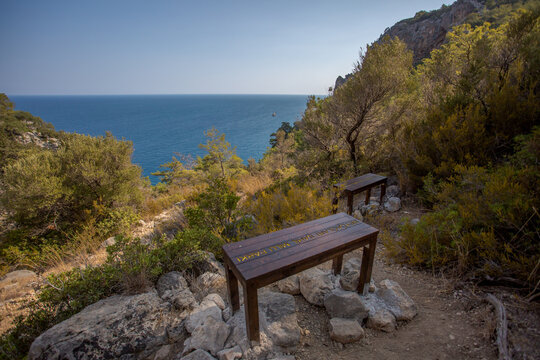 Mountain path between Kemer and Kirish. Top view from the mountain to the sea. Mountain landscape. A walk in the mountain forest. Trees in the mountains.Benches for recreation.
