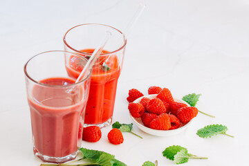 2 glasses with smoothie and drinking straws made of glass. Healthy eating and sustainability. Smoothie made from raspberries and other red fruits. Zero waste and reusable drinking straws made of glass