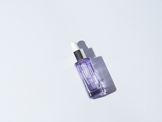 Hyaluronic acid serum peptide purple glass bottle on gray background