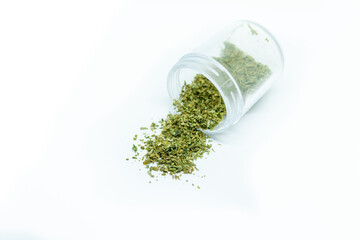Ground buds of medical marijuana stored in plastic jar. Closeup on medical hemp blend isolated on white background. CBD, medical hemp in container.