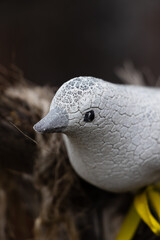 Fake clay bird sitting on old tree branch. With yellow band  in  blurred background.