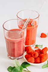 2 glasses with smoothie and drinking straws made of glass. Healthy eating and sustainability. Smoothie made from raspberries and other red fruits. Zero waste and reusable drinking straws made of glass