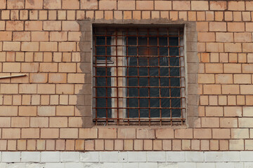 Brick wall and a window with a rusted bars
