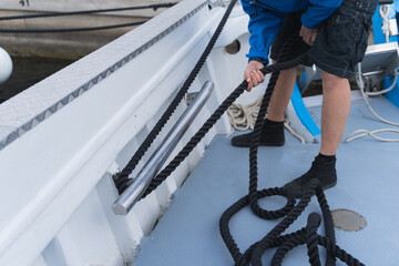 Hands pulling a rope from a ship moored on a pier