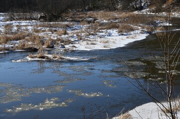picturesque landscape of early spring on the river on a sunny day. Snow melting, nature awakening