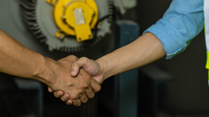 Two hands shaking together in front of machine, concept for trust and joining cooperation