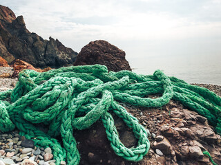 The green mooring line lies on the rocks, waiting for the ship to return.