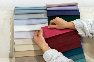 The woman chooses the fabric on the sofa. Textile industry background.
