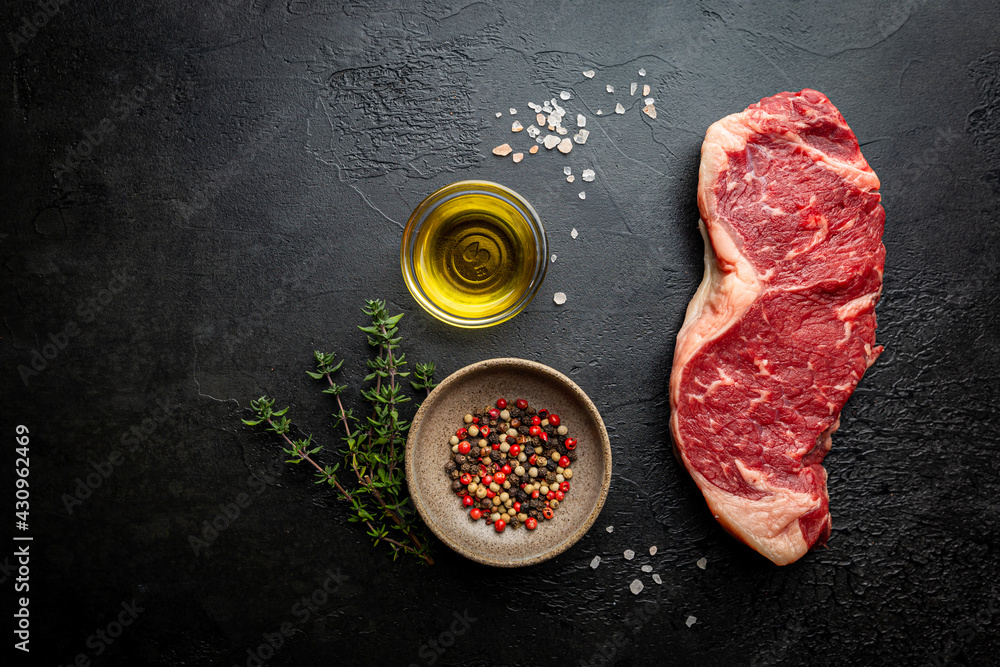 Wall mural raw fresh meat new york beef steak on black background, top view