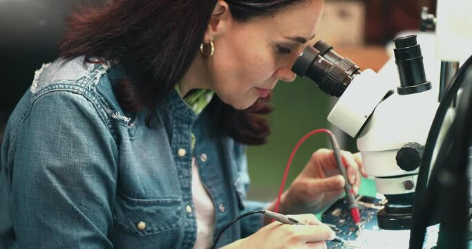 Female engineer quality inspector is checking the item, testing and fixing a circuit board