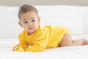 Portrait and focus to eye adorable baby child on white bed in bedroom look at camera with bright soft light in morning in background