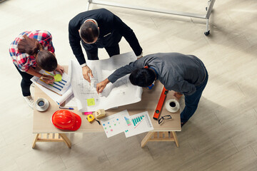 Group of engineers and boss in a formal suit working and brainstorming in construction office, taken from high angel top view