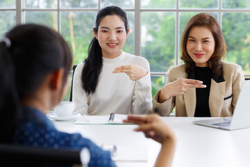 Deaf translator teaching two businesswomen to use and understand hand language sign