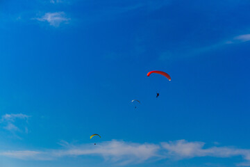 Paragliding in blue sky. Parachute with paraglider is flying. Extreme sports, freedom concept