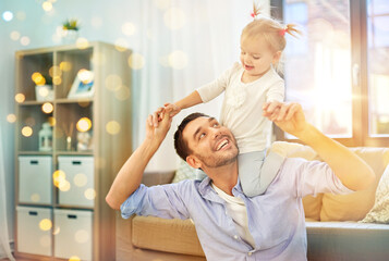 family, parenthood and fatherhood concept - happy father riding little baby daughter on his neck at home