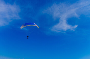 Paragliding in blue sky. Parachute with paraglider is flying. Extreme sports, freedom concept