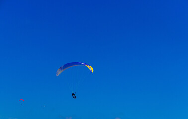 Paragliding in blue sky. Parachute with paraglider is flying. Extreme sports, freedom concept