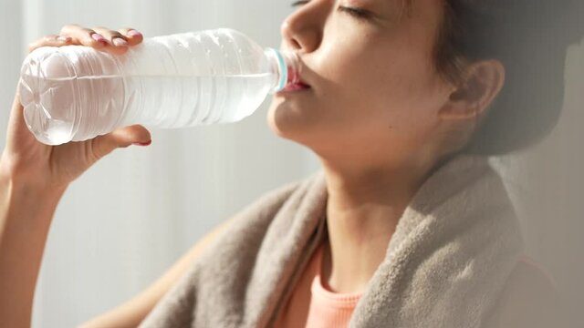 水を飲むスポーツウェアの若い女性