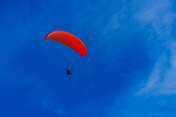 Paragliding in blue sky. Parachute with paraglider is flying. Extreme sports, freedom concept