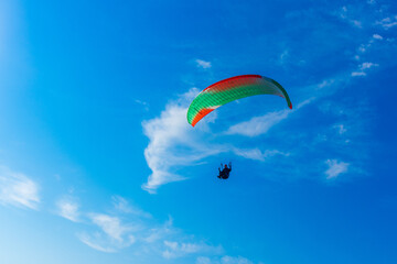 Paragliding in blue sky. Parachute with paraglider is flying. Extreme sports, freedom concept