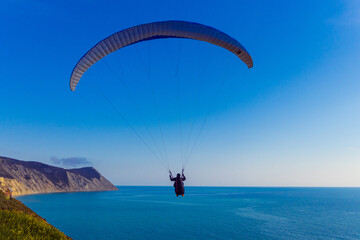 Paraglider flying above rocky coast of the black sea near the city of Anapa