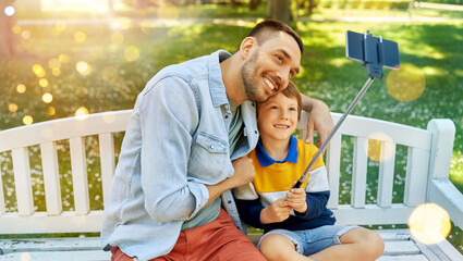 family, fatherhood and people concept - happy father and his little son taking picture with...