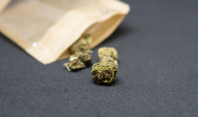 Buds of medical marijuana stored in paper bag. Closeup on medical hemp on dark background. CBD, medical hemp in container