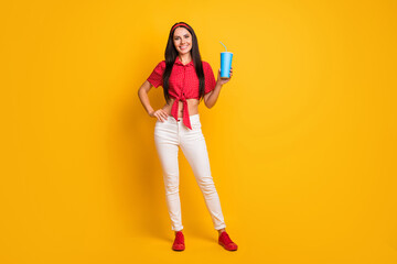 Full length photo of pretty cute young girl dressed red shirt holding blue soda glass isolated yellow color background