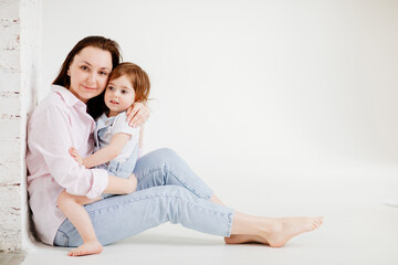 Fototapeta premium beautiful happy family sit on floor and cuddle in white photo studio.