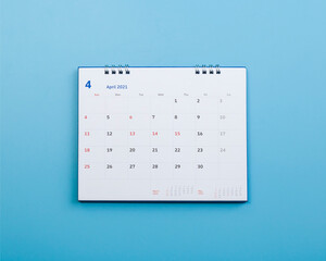 White calendar laying on blue background planning concept.	