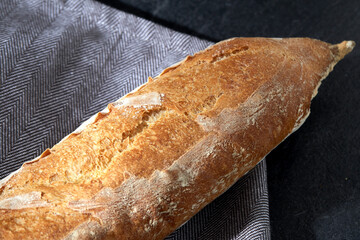 food, baking and cooking concept - close up of baguette bread on kitchen towel