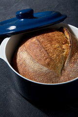 food and cooking concept - homemade craft bread in ceramic baking dish on table
