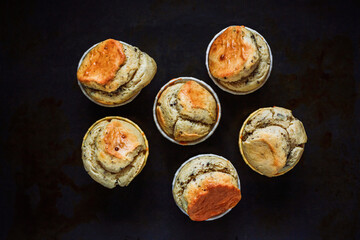 A vintage styled low-key photo of peanut butter chocolate muffins on the old used baking sheet. Soft, selective focus.