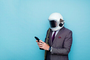 Businessman with astronaut helmet using smart phone - obrazy, fototapety, plakaty