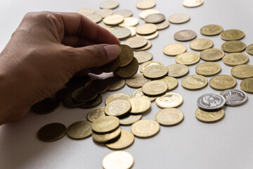 The hand of an Asian woman is holding a gold coin, low money during the coronavirus outbreak in Thailand.