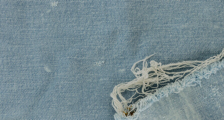 Fondo con textura de tejido vaquero en color azul claro con manchas blancas, desgastes y flecos © Coni Nicolau
