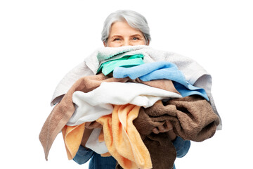 cleaning, laundry and old people concept - senior woman in denim shirt with heap of bath towels...