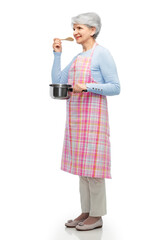 food cooking, culinary and old people concept - portrait of smiling senior woman in kitchen apron with pot and spoon over white background