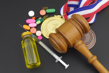Doping in sport. Judge gavel, medals and tablets with syringe on black table