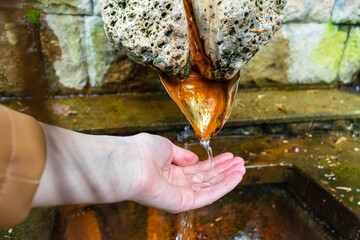 water flows from a spring a person takes water in the palm of his hand, the city is a hot spring, a...