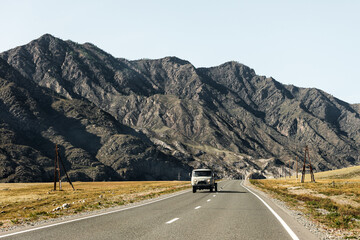 Russia, Altai, mountain landscape. Road with an old car, mountains and fields