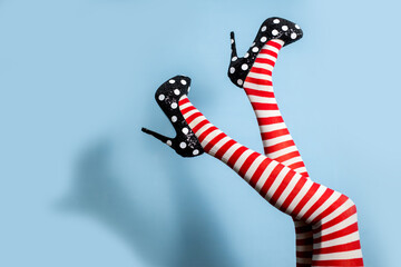 Female legs wearing striped tights over blue background