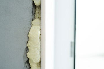 Fragment of plastic slopes in the window opening installed using polyurethane foam. Close-up - obrazy, fototapety, plakaty