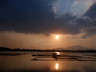 Serene, romantic and beautiful golden sunset over lake fishing farm at dawn. silhouettes