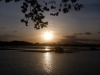 Fototapeta na wymiar Serene, romantic and beautiful golden sunset over lake fishing farm at dawn. silhouettes
