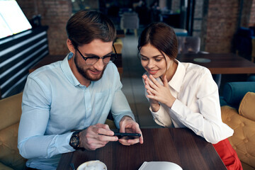 man and woman sitting at the table near the phone communication of work colleagues