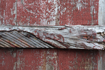 Old white wood covered with dried and disappearing red paint.