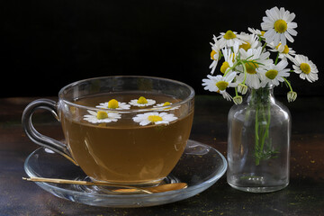 Chamomile herbal tea with flower buds on wooden table with chamomile bouquet, healthy herbal drinks and natural healer concept